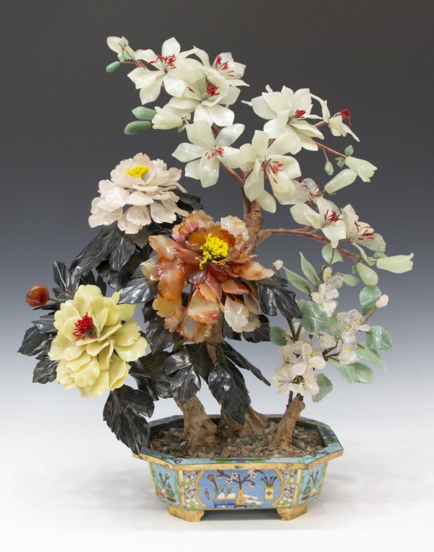 LARGE CHINESE FLOWERING HARDSTONE CLOISONNE TREE: Chinese hardstone tree, various flowering branches of rose quartz, jade, carnelian, set in a footed cloisonne enamel pot having flowers amid cartouches enclosing scholar table items, loss to corner of