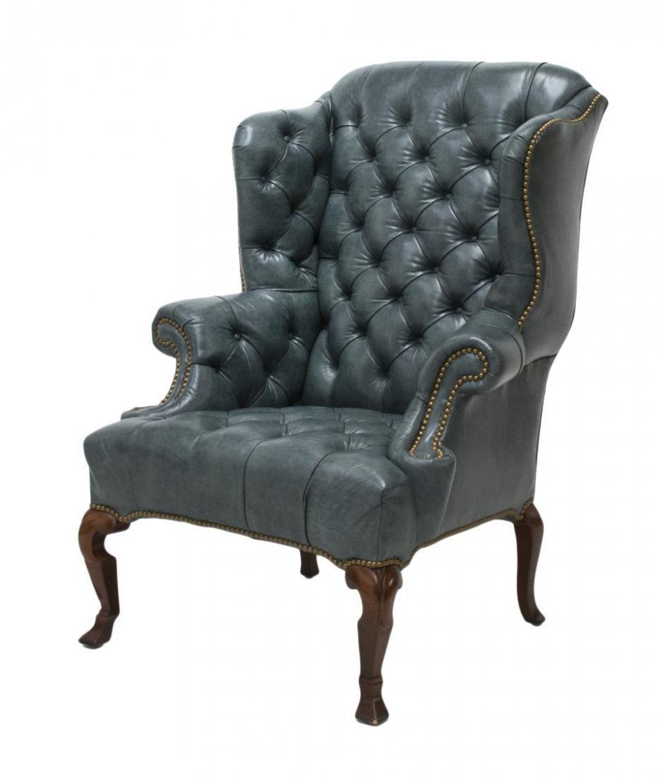 BUTTONED LEATHER WINGBACK ARM CHAIR: Wingback arm chair upholstered in buttoned blue leather, rising on carbriole legs with spade feet, 46"h, 33"w, 28"d Start Price: $200.00