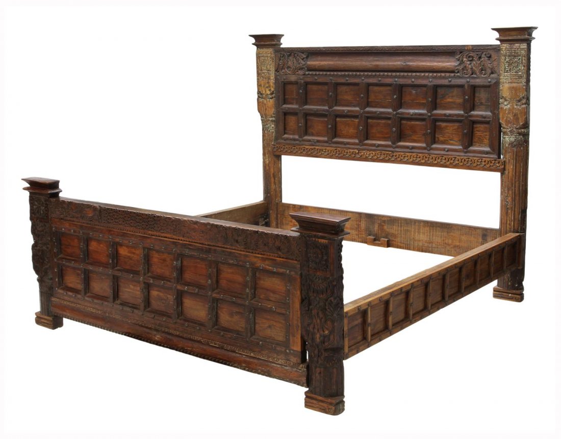 TEAKWOOD CARVED AND IRON ACCENTED KING SIZE BED: Carved king size teakwood bed, the headboard fashioned an earlier iron accented door with foliate carving flanked by half columns, remnants of polychrome decoration, a shorter conforming footboard, he