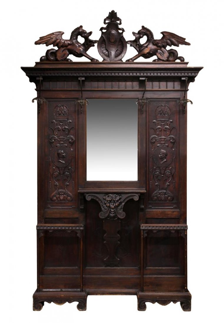 RENAISSANCE REVIVAL MIRRORED HALL TREE: Renaissance Revival hall tree, c. 1900, having a large carved crown with winged griffins holding a central shield over the protruding cornice with dentil frieze molding, the central mirror with mask s