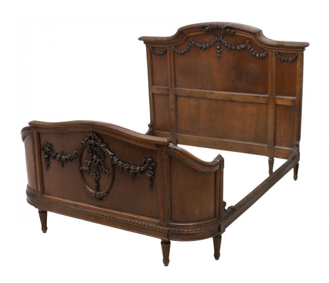 LOUIS XVI STYLE CURVED END BED: Louis XVI style walnut bed, late 19th c., decorated with floral garlands, the curved end footboard with a large wreath, rising on tapered turned ribbed legs, lacking wreath on headboard, interior: app