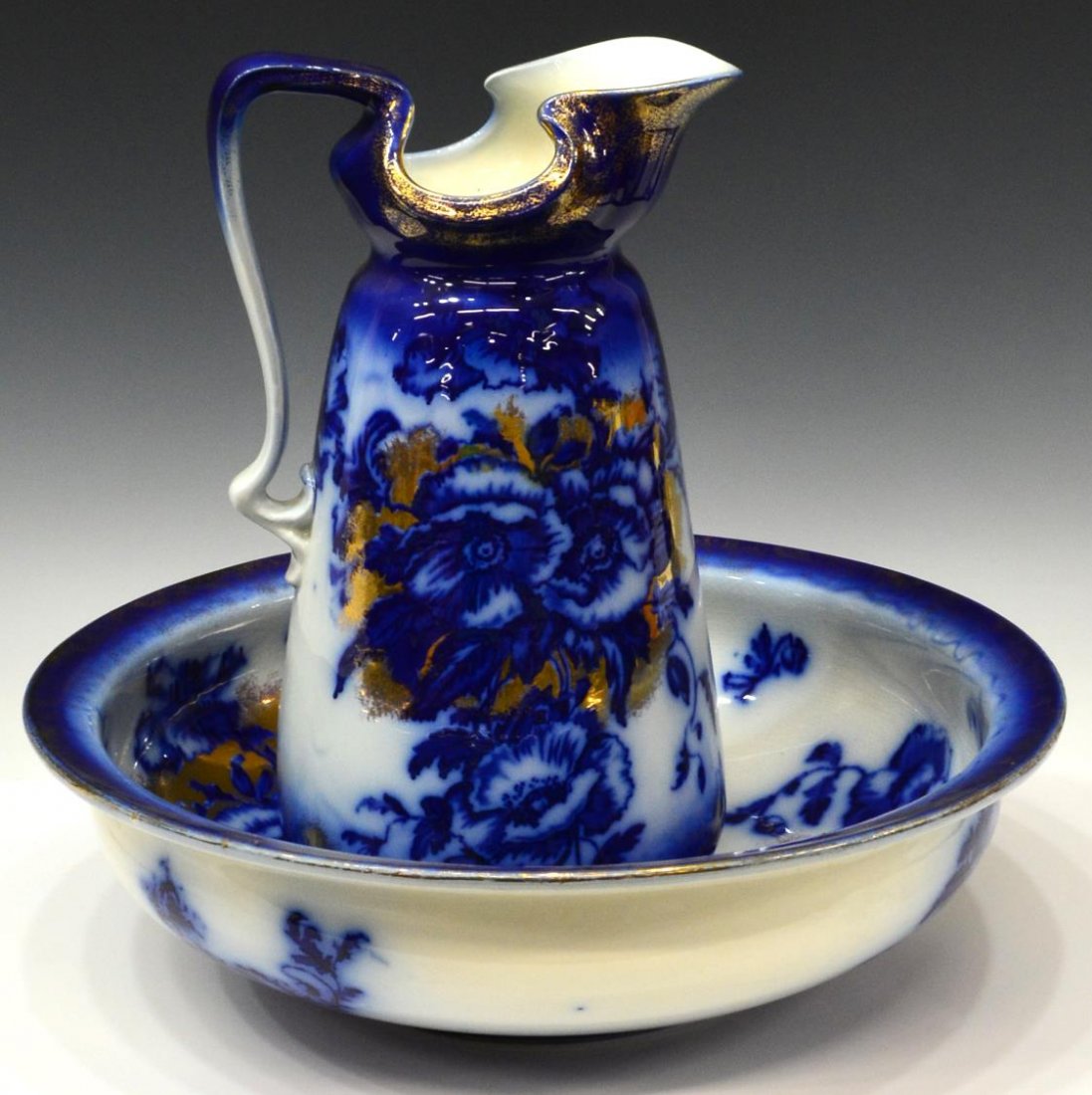 (2) LARGE VICTORIAN FLOW BLUE PITCHER & BOWL: (set) English Victorian parcel gilt ceramic flow blue pitcher and bowl, deep blue floral decor with gilded accents on the large pitcher and basin, the pitcher with chip at base side rim and glaze flak