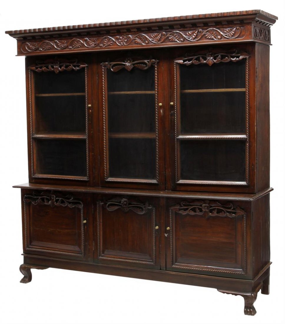 EARLY 20TH C. BRITISH COLONIAL DISPLAY CABINET: British Colonial mahogany display cabinet, early 20th c., having a stepped molded cornice over the foliate carved frieze, three glass doors with foliate carving, the lower cabinet with three doors, ri