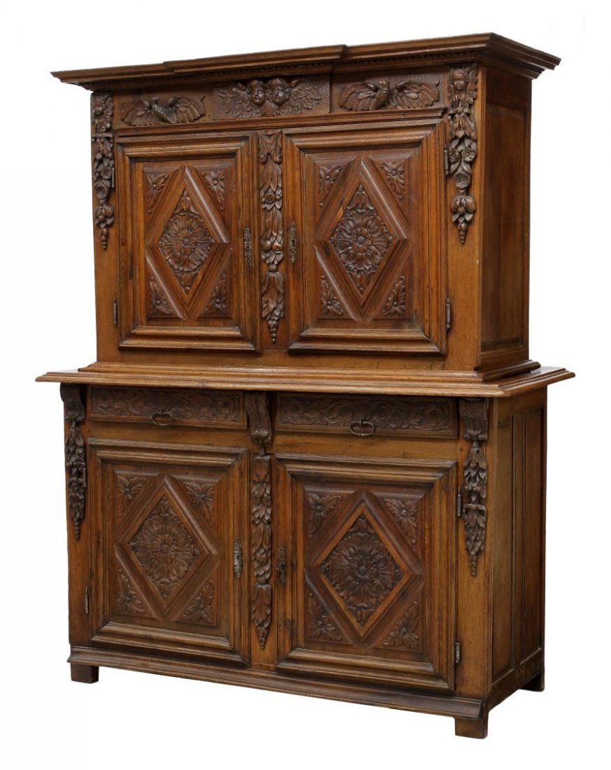 OAK FIGURAL CARVED 18TH C. CABINET: Oak figural two part cabinet, 18th c., a stepped cornice over the frieze carved with eagles and winged putti, two doors with foliate carved panels, the lower cabinet with two frieze drawers over two d