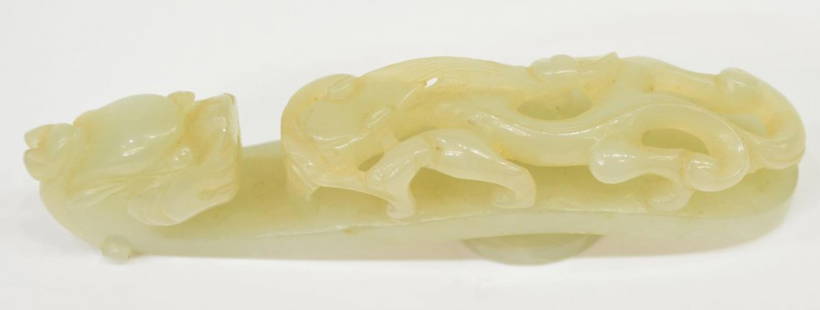 CHINESE CARVED PALE CELADON JADE GARMENT HOOK: Chinese carved pale celadon jade garment hook, of characteristic shape carved and pierced with a chilong confronting a dragon-head, 3.75"l, 51 grams Start Price: $150.00