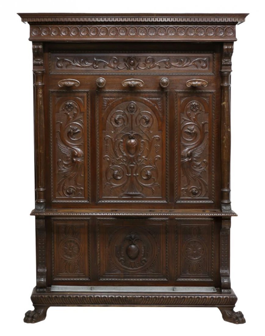 ITALIAN RENAISSANCE REVIVAL CARVED HALL TREE: Italian Renaissance Revival hall tree with mask, foliate and griffin decoration, late 19th c., the protruding cornice with geometric carved frieze over the paneled back with five coat hooks, a lower s
