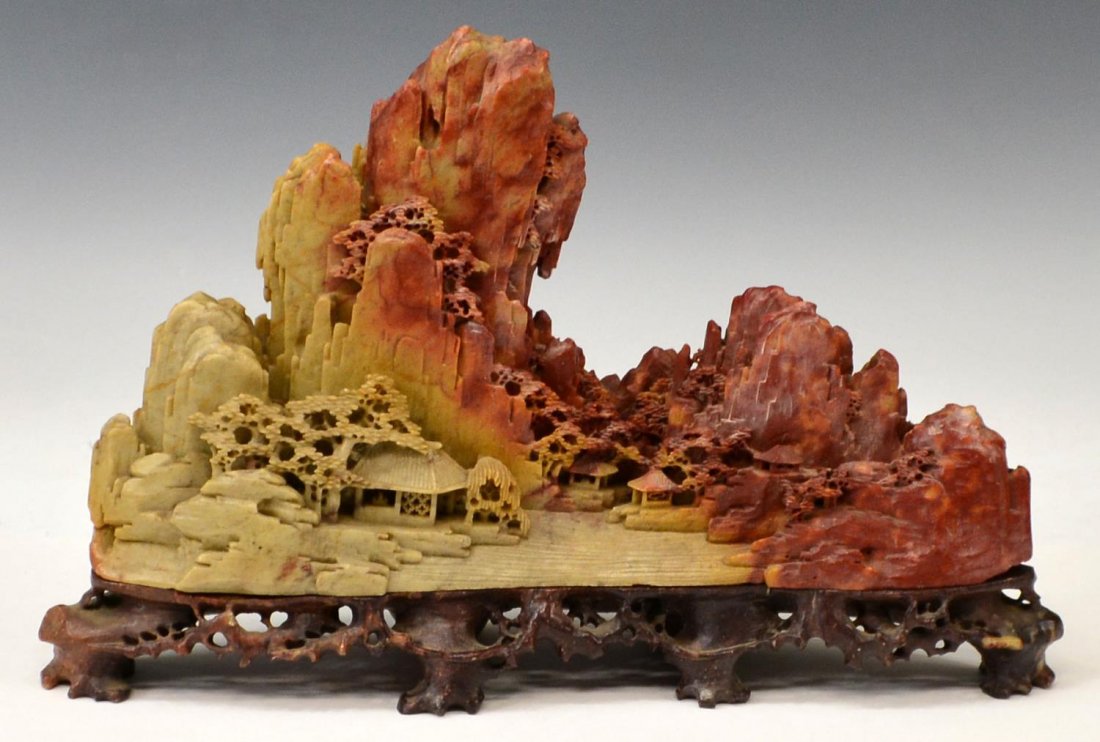 CHINESE SOAPSTONE MOUNTAINOUS LANDSCAPE CARVING: Chinese soapstone landscape carving, mountains, pagodas and pine front a mountainous backdrop, hues of rust and green, mounted on pierced contrasting base, overall: 8.5"h, 13.5"w, 7.75lbs Start Price: