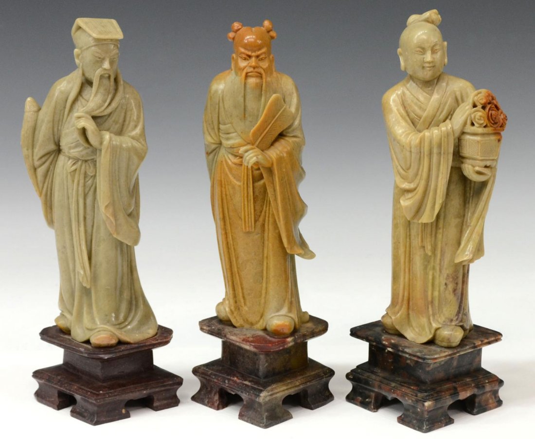 (3) CHINESE SOAPSTONE FIGURAL CARVINGS, IMMORTALS: (lot of 3) Chinese carved soapstone Immortal figures, (1) Zhong Li Quan, (1) Lan Cai-he and (1) Lu Dongbin, each robed figures standing upon a contrasting base holding their respective attribute, 10"h