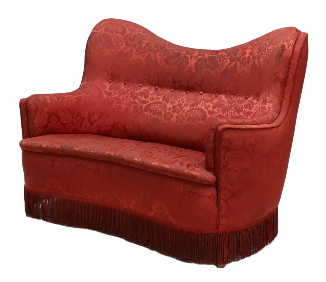 RED FLORAL BROCADE & FRINGED CURVED SOFA: Scandinavian curved sofa in red floral brocade upholstery, the shaped back joined to slightly curving arms and padded seat, fringed trim, staining to upholstery, 39"h, 49"l, 29"d Start Price: $150.00