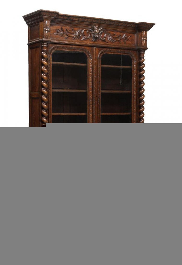 ANTIQUE FRENCH CARVED OAK BOOKCASE: French oak two part bookcase, 19th c., ex. Hotel Aiglon, Menton, France, a stepped cornice with protruding corners over the mask and foliate carved frieze, two glazed doors flanked at each side by twi
