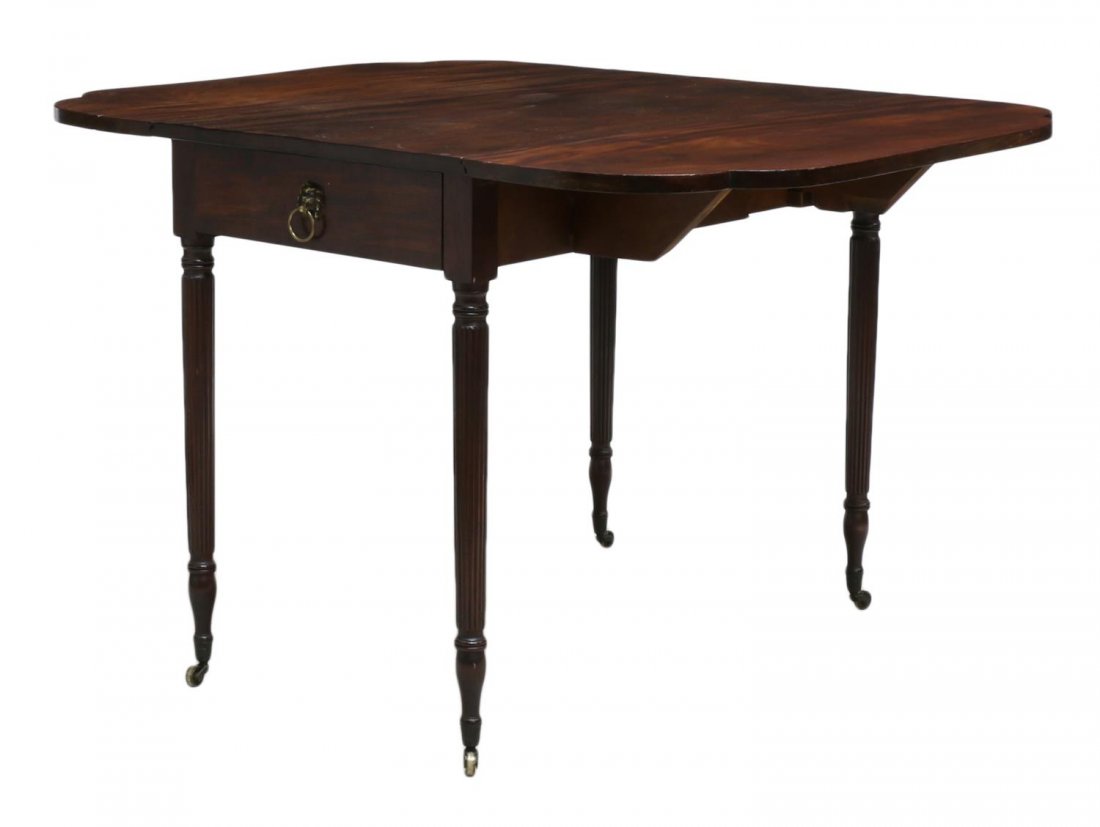 SHERATON MAHOGANY DROP SIDE TABLE ON RIBBED LEGS: Sheraton mahogany drop leaf table, England, early 19th c., one pull out drawer with scallop edge corners and ribbed legs on casters, lion head drawer pull later addition, approx 29"h, 21.5"l, 36"w, ex