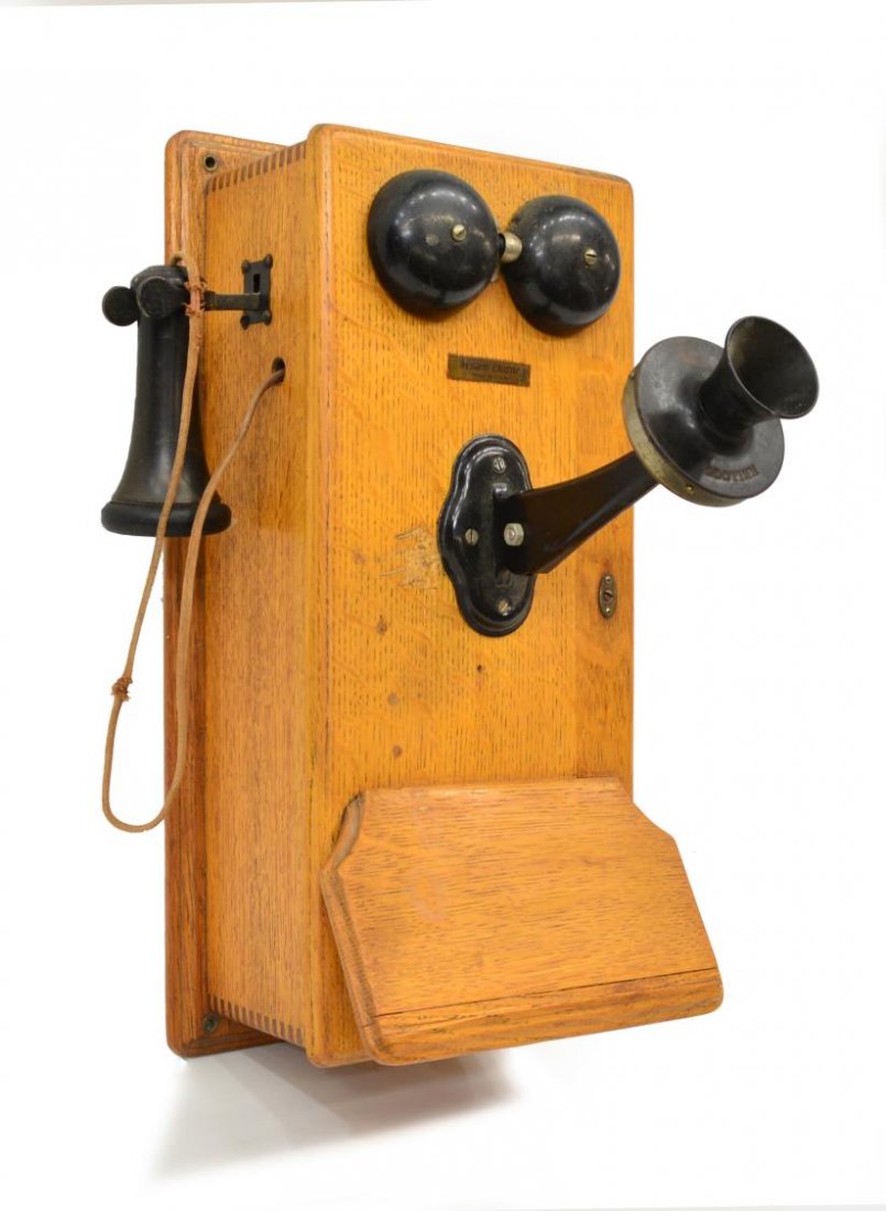 ANTIQUE WESTERN ELECTRIC CRANK WALL PHONE: Western Electric oak cased crank wall phone, early 20th c., interior with three bar magneto, cranks causing bells to ring, Kellogg mouth piece, receiver lip broken, 20.5"h, 9.5"w, 15"d Start Price: $6
