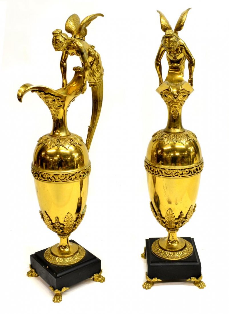 EMPIRE STYLE FIGURAL EWERS, MANNER OF C. GALLE: (pair) Empire style gilt brass ewers in the manner of Claude GallÃ©, each having an ovoid body with single handle modeled a classical winged maiden the spout having a figural mask mount, above a fri