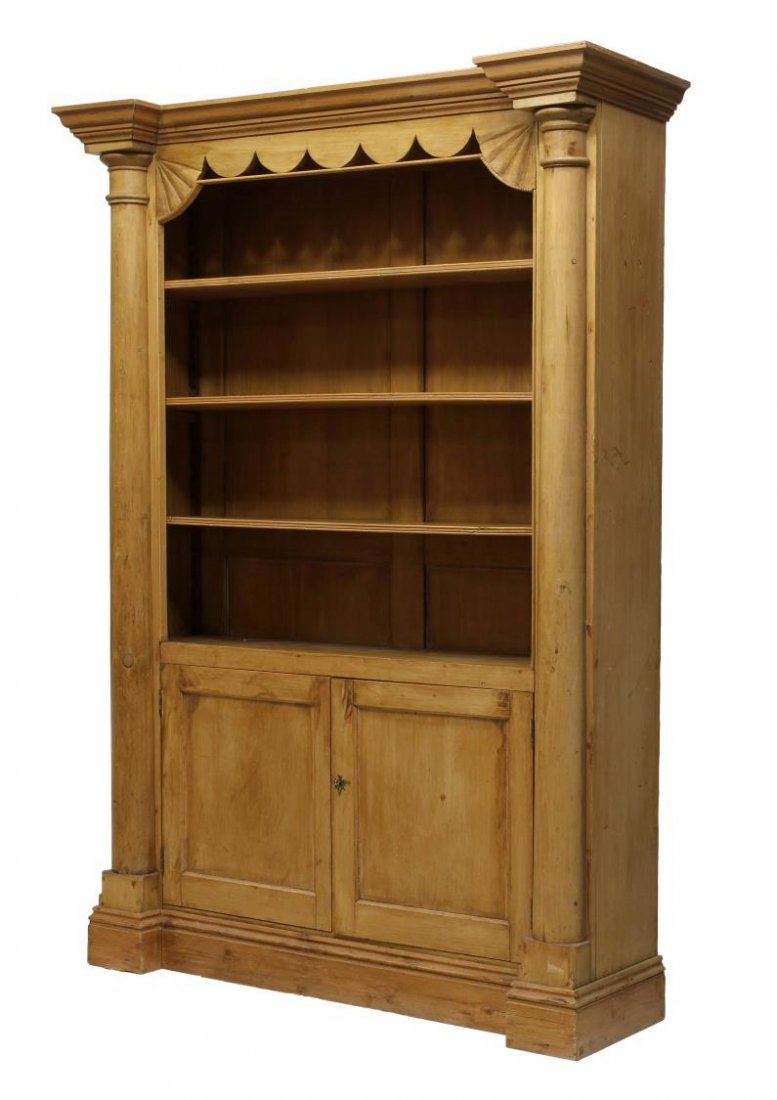 LARGE PINE BOOKCASE CUPBOARD: Large pine bookcase cupboard, 20th c., having a stepped cornice over a decorative cutout frieze, the center with adjustable height shelves over two doors, all with flanking half columns, rising on a p