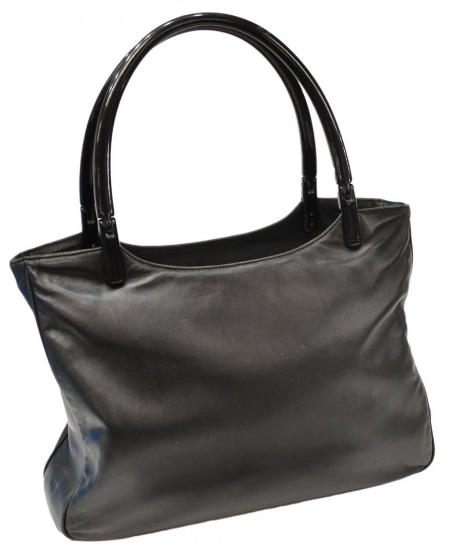 PRADA BLACK LEATHER & BAKELITE HANDLE PURSE: Prada handbag in black leather with two black bakelite handles, "Prada" imprinted on side, top opens to black logo pattern cloth interior featuring one zipper and one large velcro pocket, dust bag, me