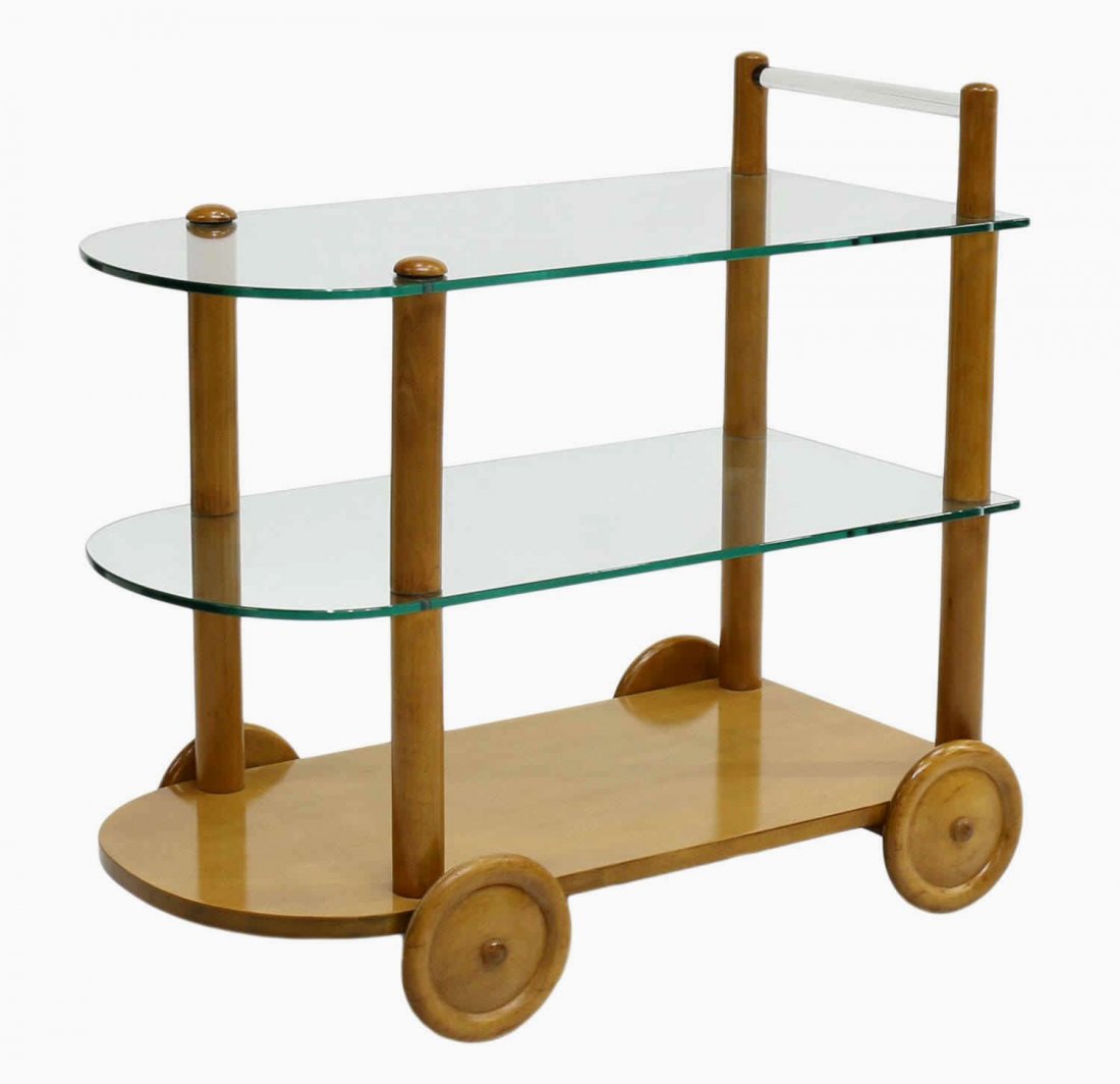 GILBERT ROHDE DESIGN SERVICE BAR OR TEA CART: Mid-century modern service, bar, or tea cart, design by Gilbert Rohde (American, 1894-1944) for Herman Miller, glass handle above two glass shelves over the lower wood shelf, all rising on wood wheels