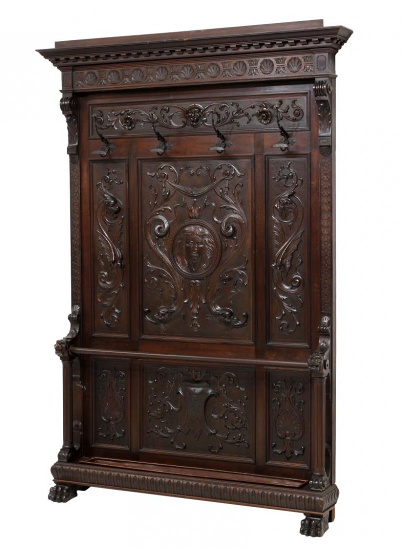 ITALIAN RENAISSANCE REVIVAL MAHOGANY HALL TREE: Italian Renaissance Revival mahogany hall tree, late 19th c., a stepped cornice with carved frieze over a foliate and mask carved panel, four large coat hooks above the three panels carved with mask, 
