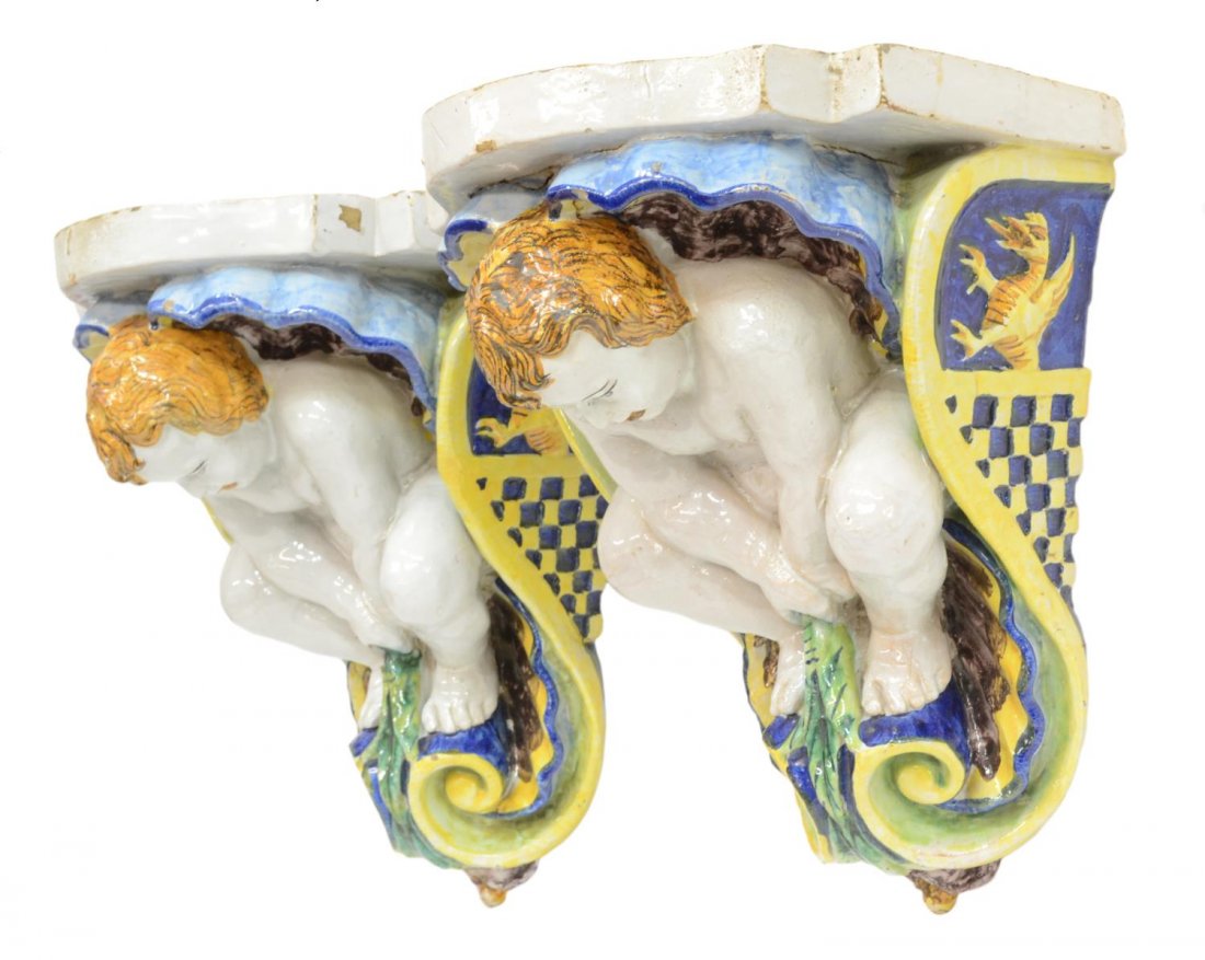 (2) ITALIAN MAJOLICA FIGURAL HANGING WALL BRACKETS: (pair) Italian majolica figural wall brackets, each having a putto in a shell with dragons in relief along the sides, unmarked, some glaze loss, approx 14"h, 11.5"w, 10"d, 26lbs total Start Price: $15