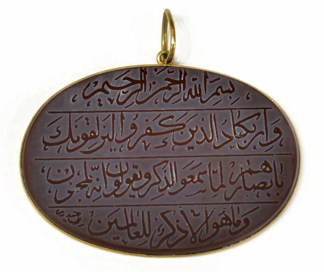 LARGE 18KT & CARNELIAN RELIGIOUS PENDANT, ARABIC: A large oval pendant, the 18kt gold bezel and bail enclosing a large carnelian stone with Arabic religious inscription, 1.75"h, 2.5"w, 25.7 grams (all inclusive) **Provenance: presented in 1973 by Gen