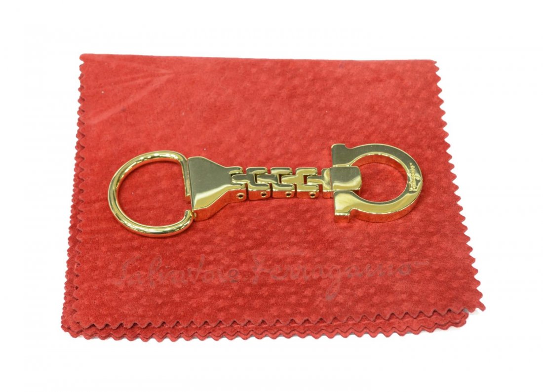 SALVATORE FERRAGAMO KEY CHAIN: Ferragamo key chain, gold tone with red cloth carrying case stamped with brand, approx 3.25"l, .25lb Start Price: $40.00