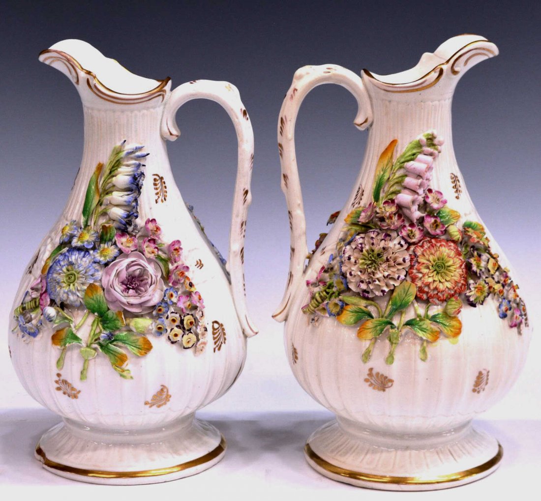 (2) ENGLISH FLORAL ENCRUSTED PORCELAIN JUGS: (pair) English floral encrusted porcelain pitchers, 19th c., possibly Coalport or Minton, each having a profusion of applied flowers against a white ground with gilt accent, unmarked, typical loss to 