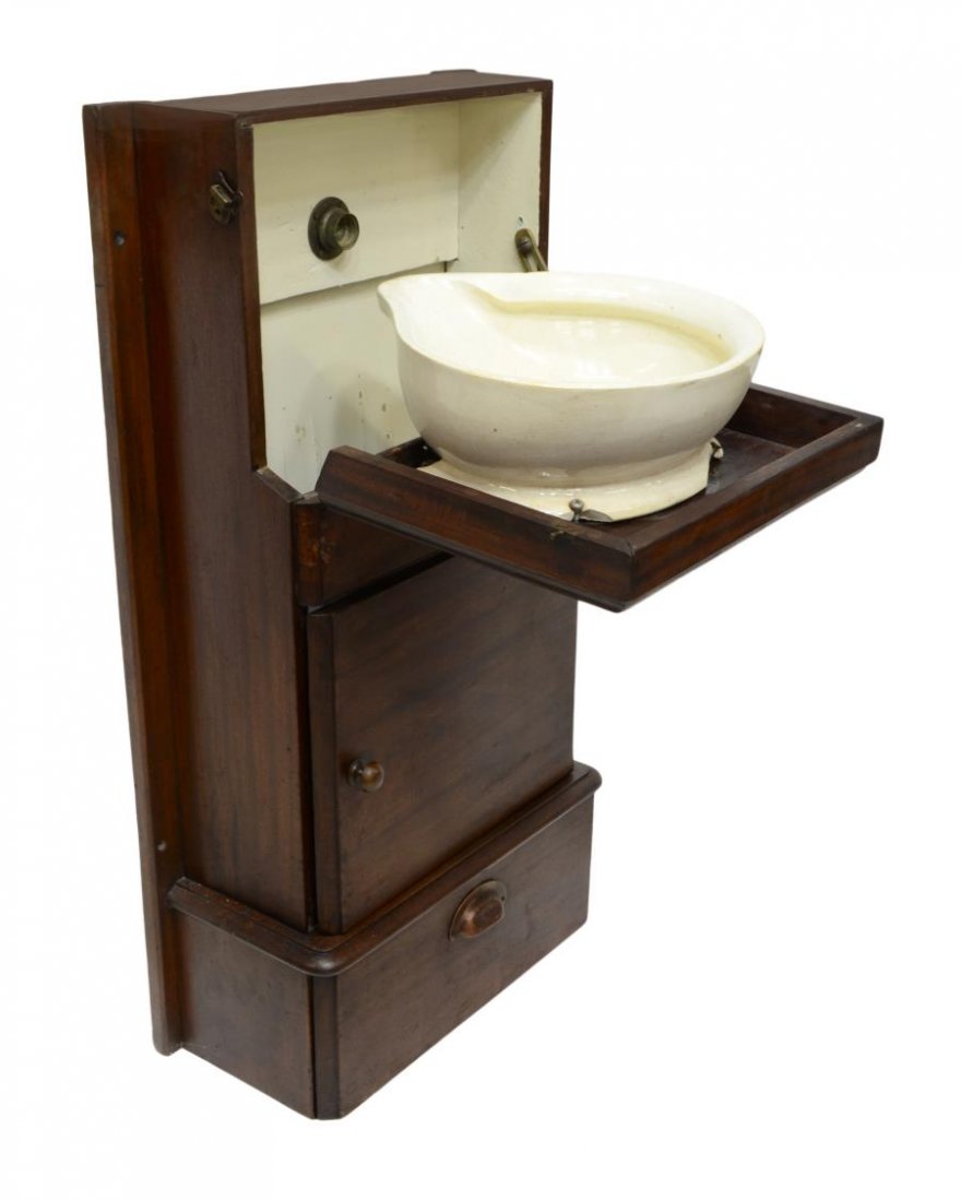 MAHOGANY CASED TILTING PORCELAIN SINK: Mahogany cased sink, 19th c., the hinged front drops to reveal a porcelain wash sink, after use the front is raised tilting the sink and allowing water to pour into a removable tin well, two lower doo