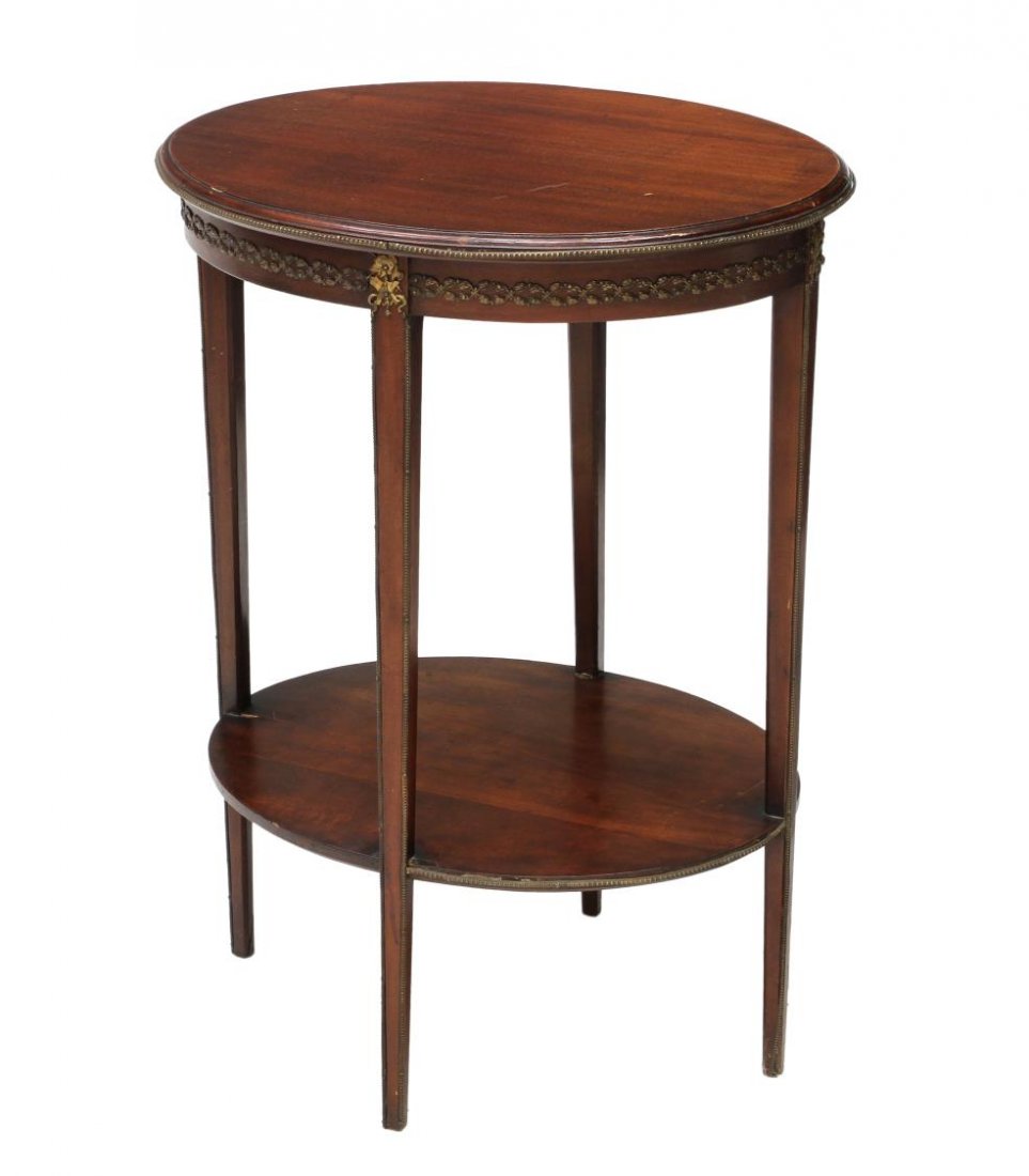 MAHOGANY OCCASIONAL TABLE: Mahogany occasional table, 20th c., an oval top accented with brass decoration at edge, the frieze with continuous brass foliate ormolu, rising on tapered squared legs joined by a lower shelf, 29.25"h