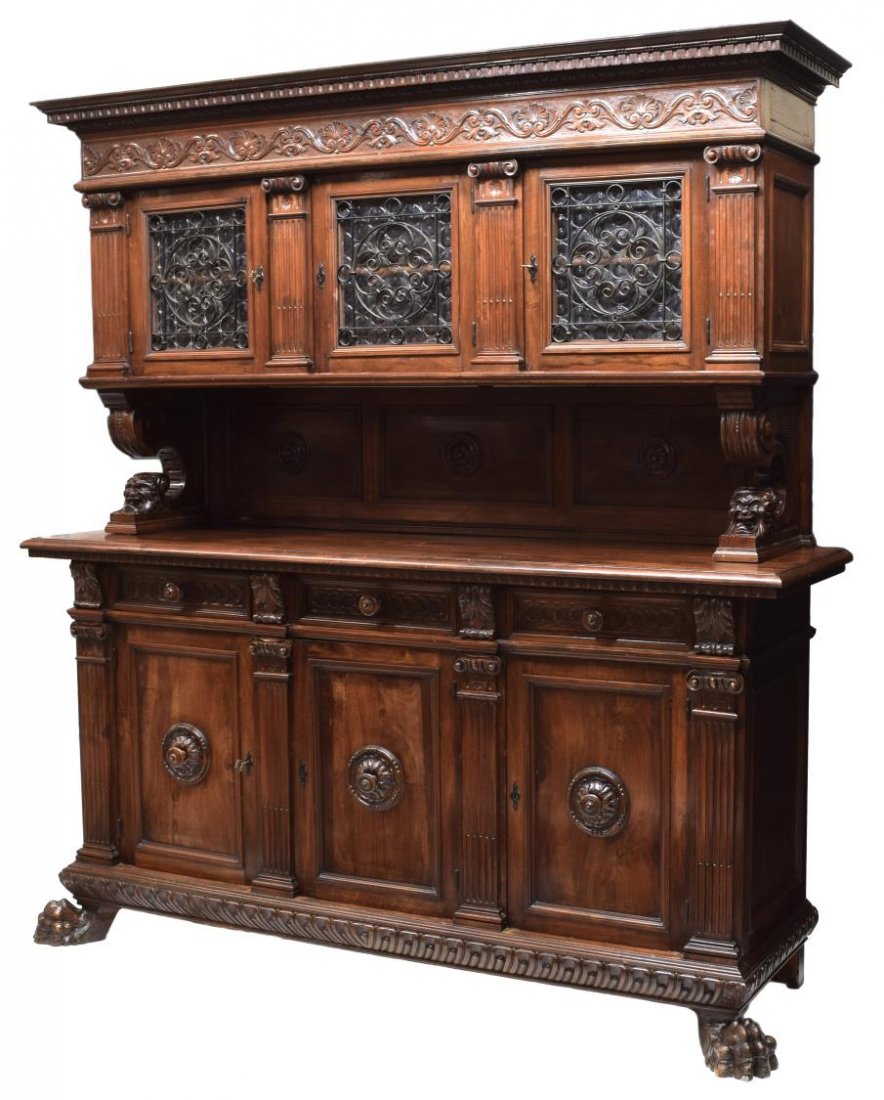 ITALIAN RENAISSANCE REVIVAL CARVED SIDEBOARD: Italian Renaissance Revival carved walnut sideboard, figural corbels support the upper case with dentil and ornamental borders, foliate carved frieze, above three bottle glass doors set with iron scro