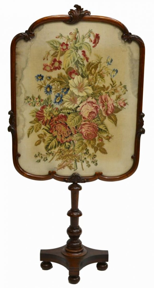 VICTORIAN FLORAL NEEDLEPOINT & WALNUT FIRESCREEN: Victorian floral needlepoint and walnut fire screen, 19th c., having a large floral arrangement embroidered with wool on linen ground, the shaped frame having foliate accents, rising from a turned col