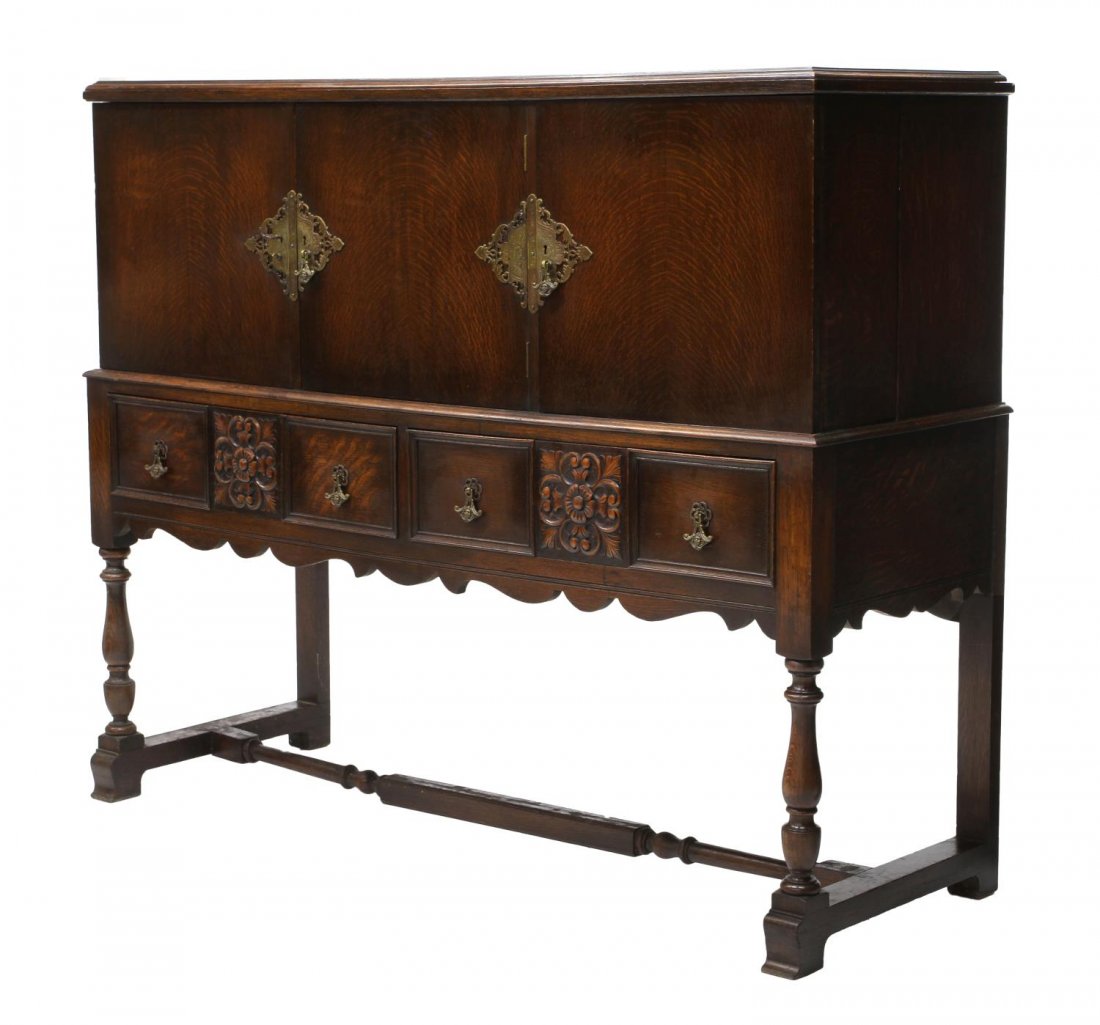 JACOBEAN STYLE CARVED OAK SIDEBOARD: Jacobean style oak sideboard, having three doors with pierced and foliate metal plates with pulls, (two) doors opening to shelves, (one) door opening to open compartment with door shelf, above two car