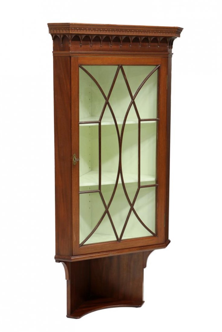 CARVED MAHOGANY CORNER CABINET: Mahogany corner cabinet, 20th c., a stepped cornice and carved frieze over the astragal faced glazed door opening to shelves, a lower open shelf, 52"h, 24.4"w, 15"d Start Price: $150.00