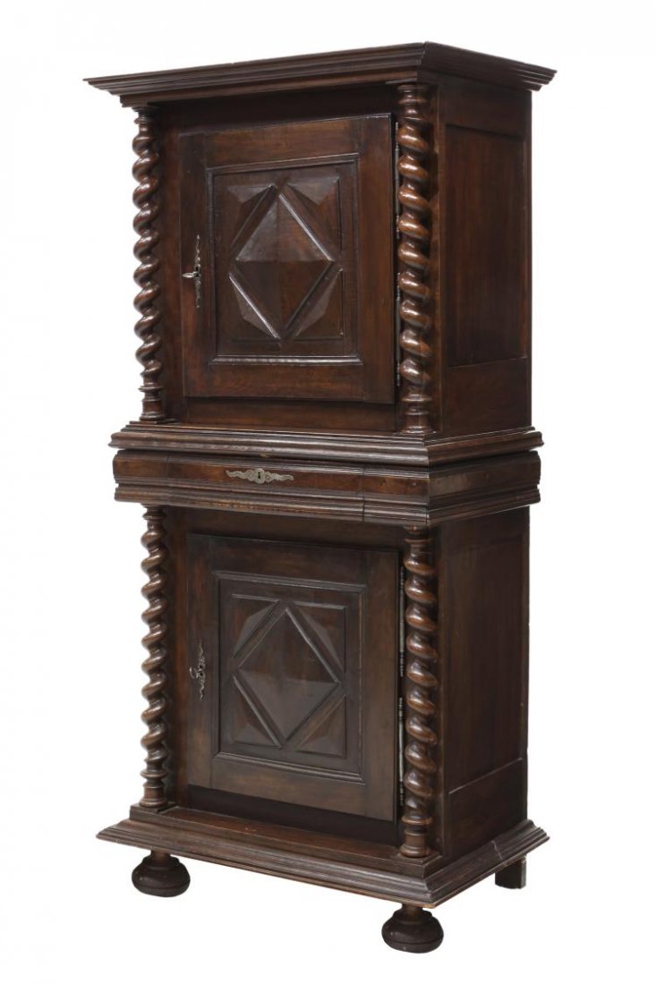 FRENCH WALNUT BONNETIERE, MID 19TH C.: French walnut bonnetiere, mid 19th c., having a stepped cornice over upper and lower doors separated by a central drawer and all flanked at each side by twist columns, the stepped base rising on bun f