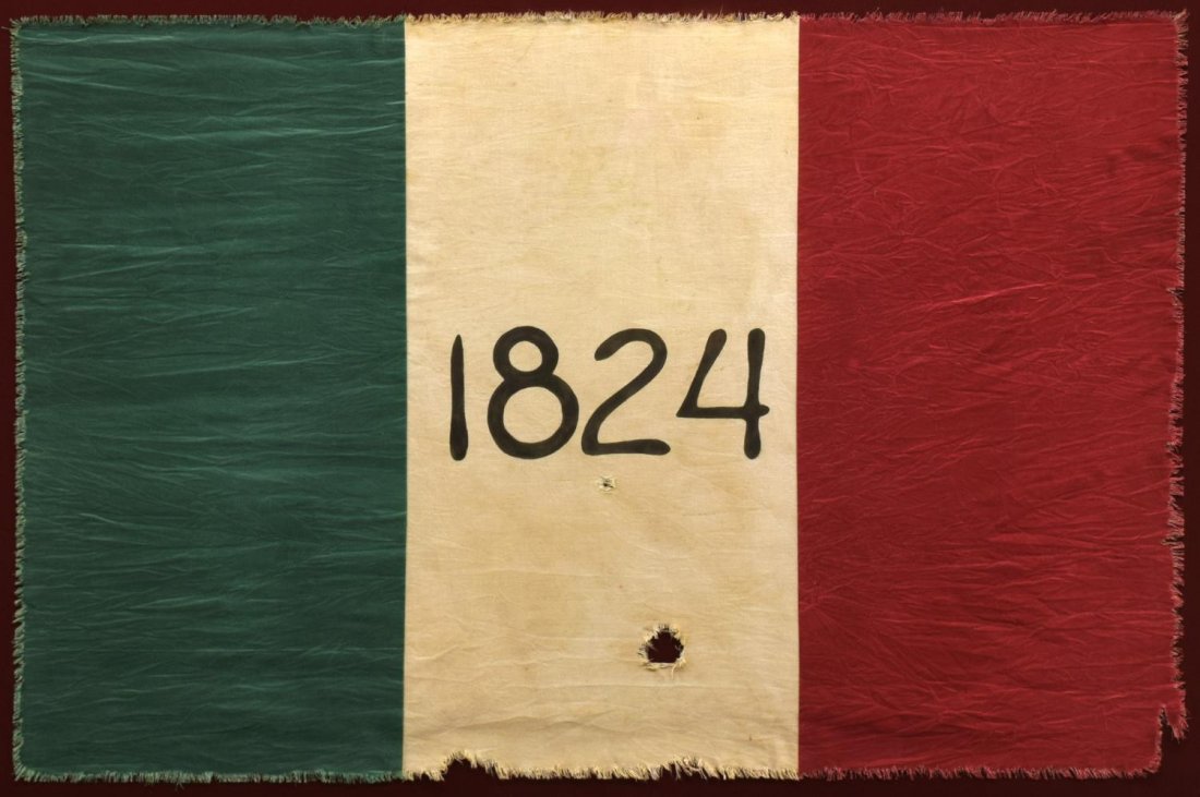 FRAMED REPLICA OF THE TEXAS ALAMO BATTLE FLAG: Shadow box framed, under glass, cloth flag, a reproduction of the Alamo Flag, originally the Mexican Flag, their coat of arms at the center replaced with the date 1824, the date of the Mexican constit