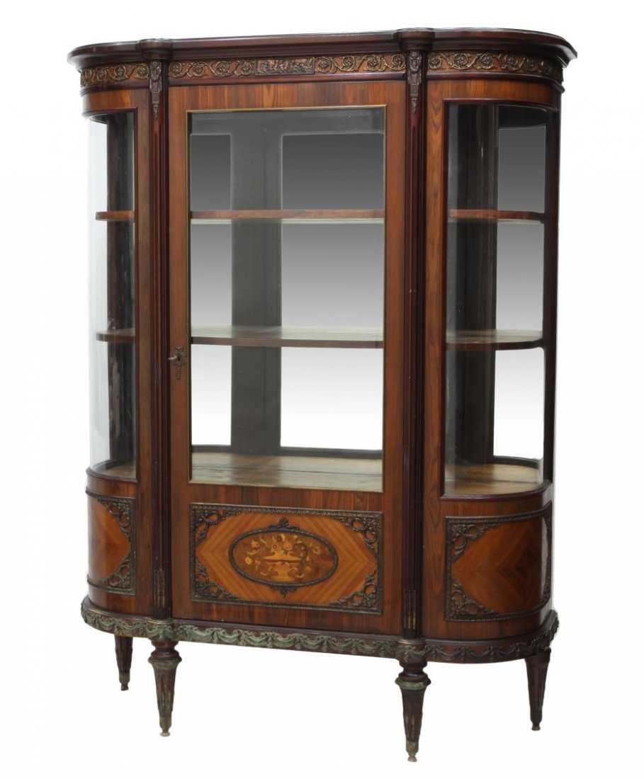 FRENCH LOUIS XVI STYLE CURVED GLASS VITRINE: French Louis XVI style vitrine, 20th c., decorated with foliate brass ormolu, the protruding cornice over a single door flaked at the sides by ribbed pilasters and curved glass panels, the mirror back