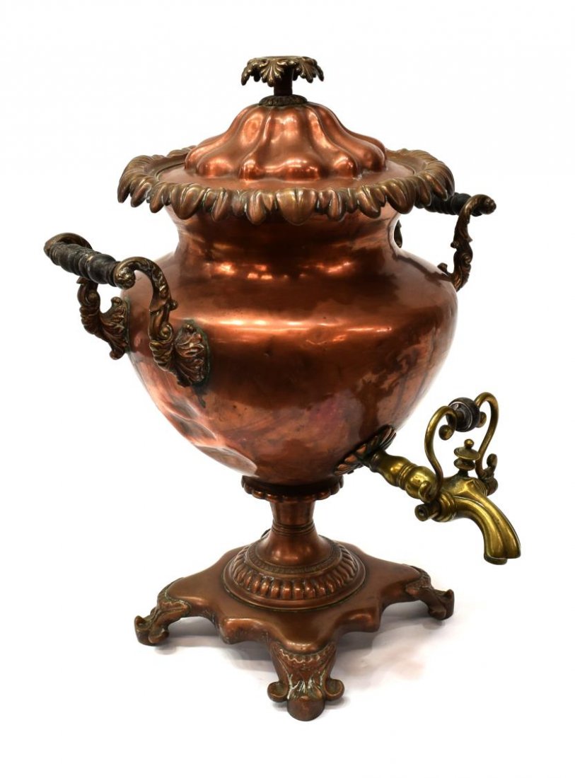FOLIATE LIDDED COPPER SAMOVAR WITH EBONY HANDLES: Copper samovar, possibly 19th c., having a foliate decorated lid over the tapered body, applied turned ebony handles, brass spigot, rising on square base with foliate feet, dented, 18"h, 13"w, 13"d, 1