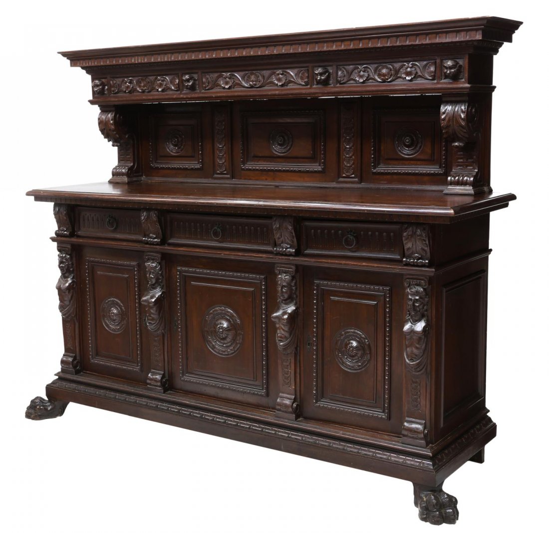 ITALIAN RENAISSANCE REVIVAL CARVED SIDEBOARD: Italian Renaissance Revival heavily carved walnut figural sideboard, early 20th c., the corniced top over mask and foliate frieze and shelved back, acanthus scroll supports above a rectangular case fi