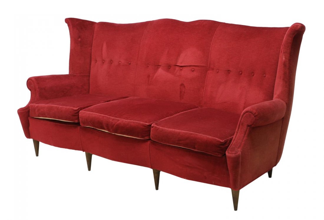ITALIAN MID-CENTURY MODERN WINGBACK SOFA: Italian mid-century modern wingback sofa, 1950's, upholstered in buttoned red fabric, a serpentine high back over the three removable seat cushions, set on turned tapered legs, 38.5"h, 83.5"w, 30"d St