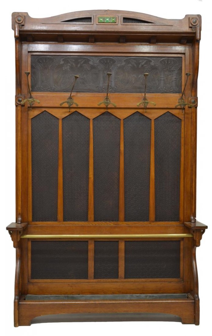 ITALIAN CARVED ART NOUVEAU HALL TREE, C. 1900: Italian arved Art Nouveau hall tree, c. 1900, the crested top fitted with three green glass inserts, above a shallow shelf, over a foliate patterned panel, with five 2-tiered coat hooks, over patterne