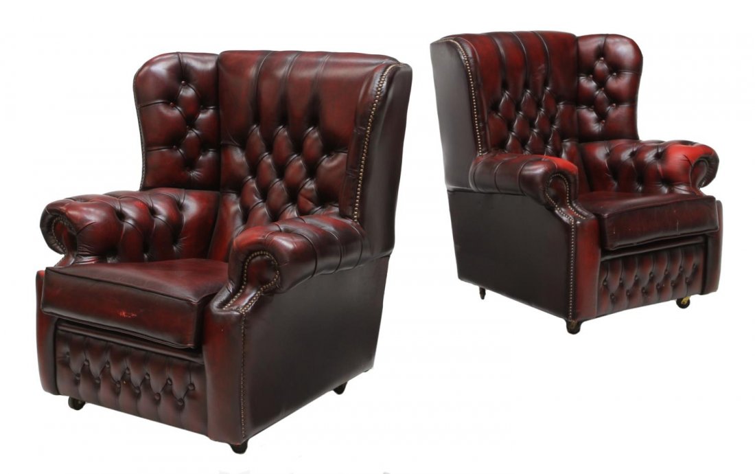 (2) CHESTERFIELD BUTTONED OXBLOOD RED WING CHAIRS: (pair) Chesterfield oxblood red wingback low chairs, each having wide buttoned back and rolled arms, loose cushion seat, accented with brass tacks, approx 34.5"h, 36.5"w, 28"d Start Price: $300.00