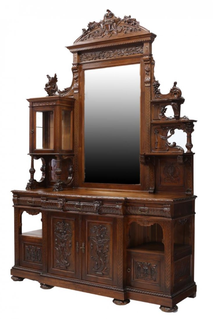 HIGHLY CARVED ITALIAN RENAISSANCE 19TH C. CABINET: Italian Renaissance Revival walnut sideboard cabinet,, 19th c., profusely decorated with masks, grapes, grotesques and foliate carving, an arched cornice over the central mirror flanked at one side by