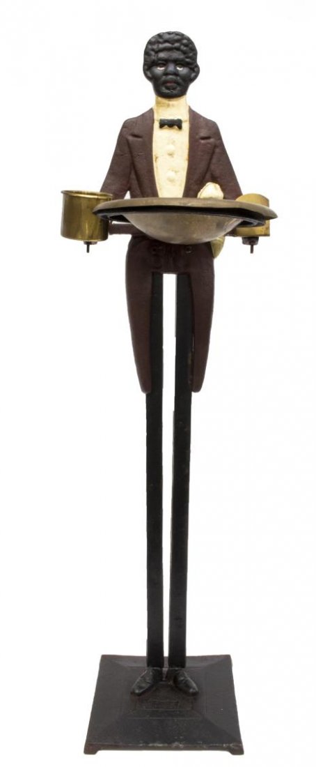 POLYCHROME TALL FIGURAL IRON BUTLER ASHTRAY: Figural polychrome iron butler seemingly holding brass ash tray, brass match holder and brass bucket, rising on long legs from the steel platform, 31.75"h, 9.5"w, 9.5"d., 10.5lbs Start Price: $100.00