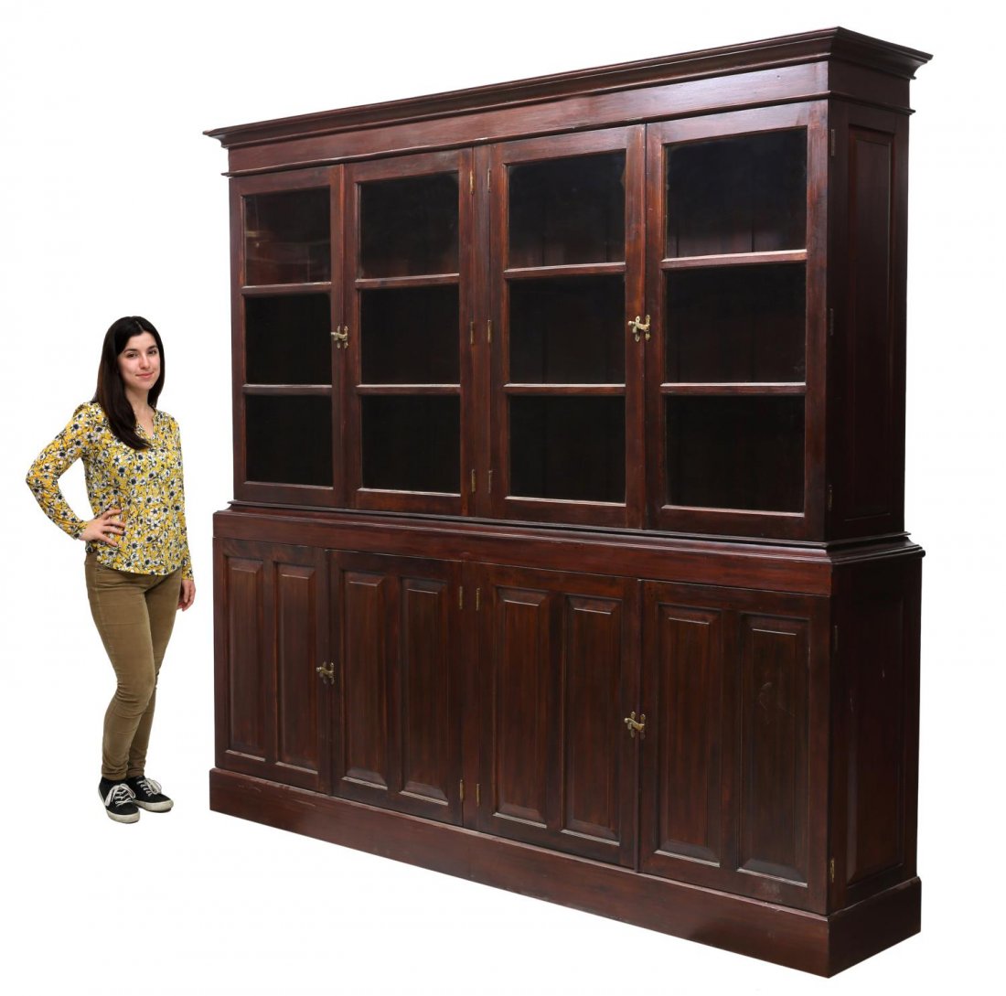 LARGE COLONIAL STYLE GLAZED & CARVED BOOKCASE: Colonial style bookcase in two-parts, Kandy, India, the upper case having overhang cornice, four glazed doors open to shelves, the base having paneled cabinet doors and interior shelf, approx 90.75"h,