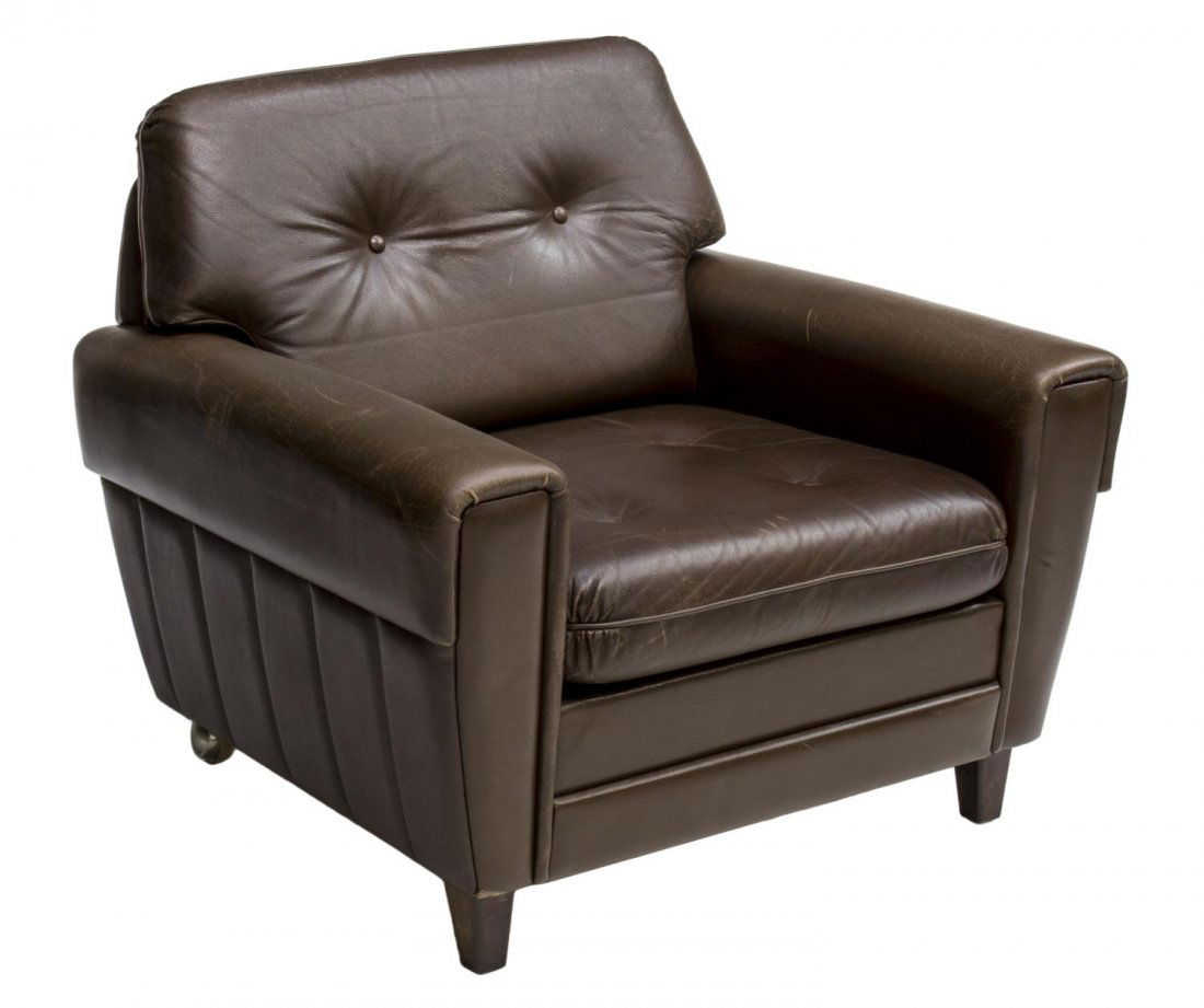 DANISH MODERN BROWN LEATHER ARMCHAIR, C. 1970: Danish modern brown leather armchair, c. 1970, the low back issuing removable back and seat cushions, pleated detail to sides, rising on casters, 26"h, 33"w, 30.5"d Start Price: $80.00