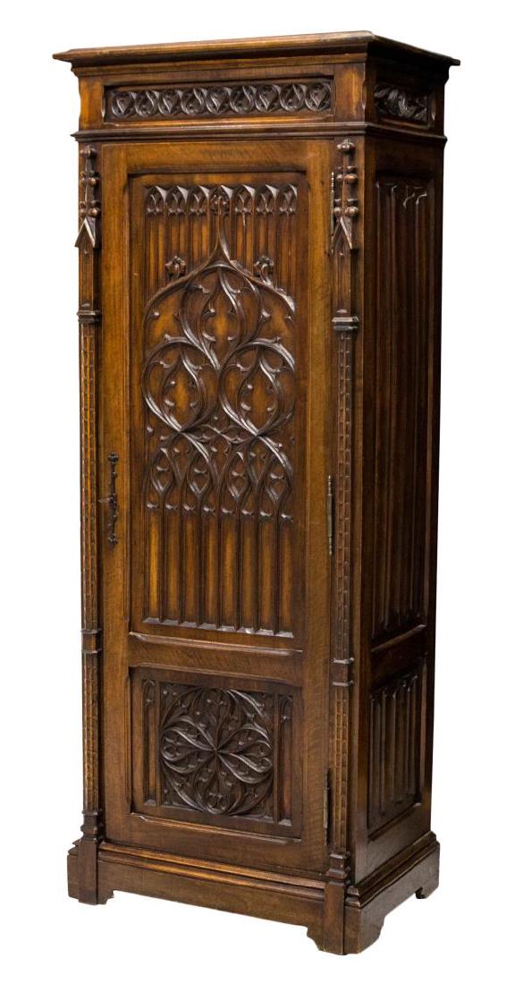 FRENCH GOTHIC REVIVAL CUPBOARD: French Gothic Revival cupboard, 19th c., decorated with tracery, arches, spiral half columns, line fold, and other Gothic accents, the protruding cornice with figural frieze over a single door, rising