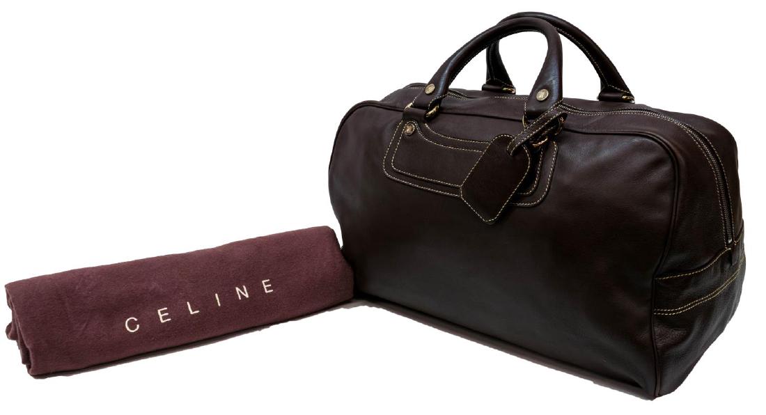 CELINE BROWN LEATHER DOUBLE HANDLED DUFFLE BAG: Celine Paris duffle bag in brown leather, having silver tone hardware, double handles over a zipper top, opening to monogram fabric interior, with zipper, slot, and cell pockets, retaining luggage tag
