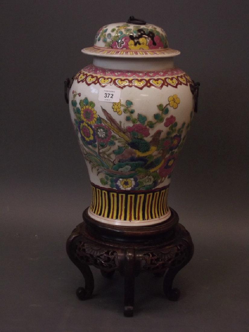 A Chinese porcelain jar and cover with enamel: A Chinese porcelain jar and cover with enamel decoration of pheasants amongst flowers, on a carved wood stand, 6 character mark to base, jar 14" high
