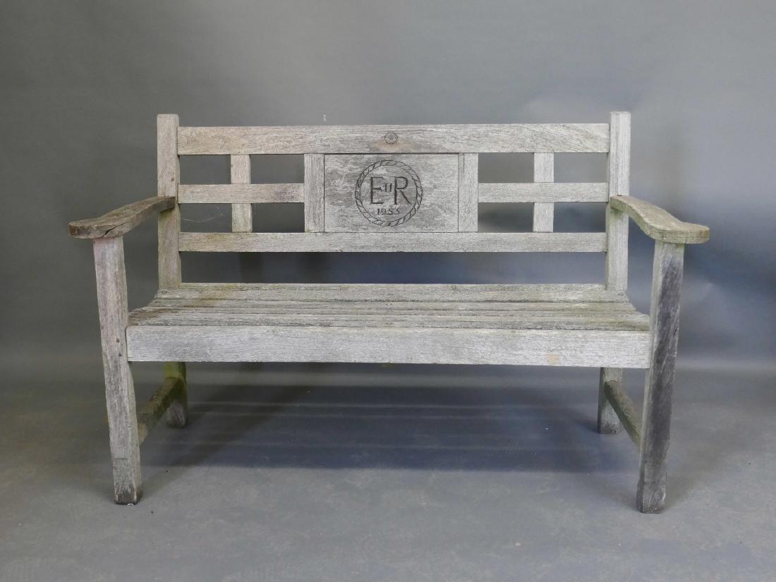 A weathered teak garden bench with carved back: A weathered teak garden bench with carved back commemorating the Coronation of Elizabeth II in 1953, 52" wide