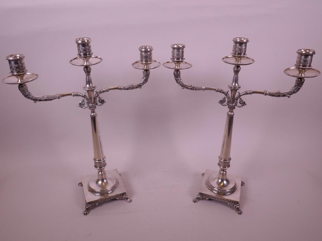 A pair of French silver Empire style three branch table: A pair of French silver Empire style three branch table candelabra, with cast arms on tapered column, and plinth base raised on paw feet, 14 1/2" high, gross 1545 grams