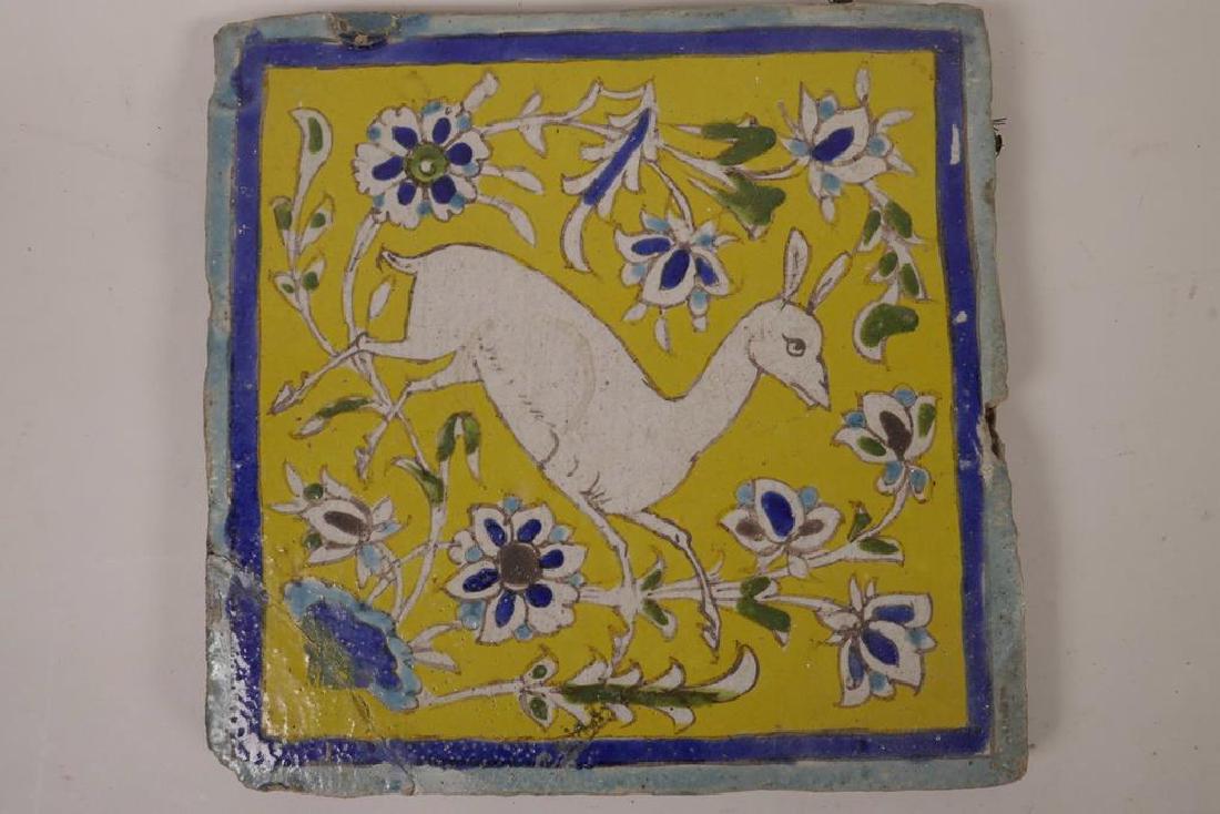 An antique Iznik pottery tile painted with a deer: An antique Iznik pottery tile painted with a deer amongst flowers in bright enamels, 9½" square, A/F