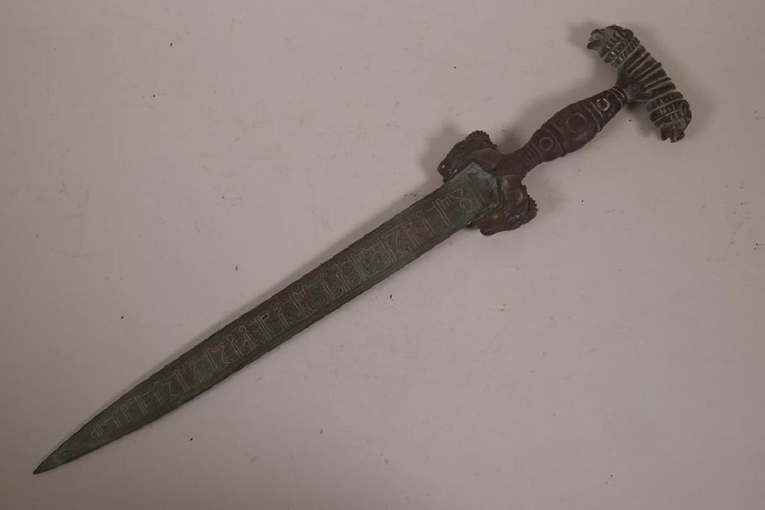A Middle Eastern ornamental bronze short sword, with: A Middle Eastern ornamental bronze short sword, with lion mask and ram's head decoration, the blade inlaid with Islamic calligraphy, 22" long